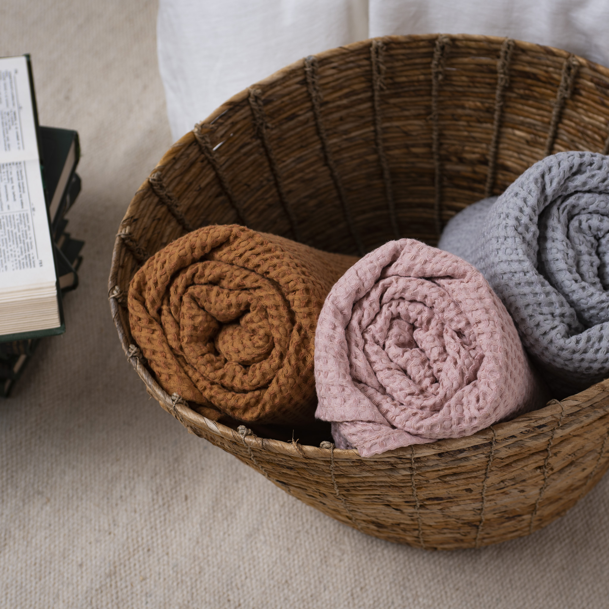 Handmade waffle weave linen textiles in natural colors displayed in wicker basket