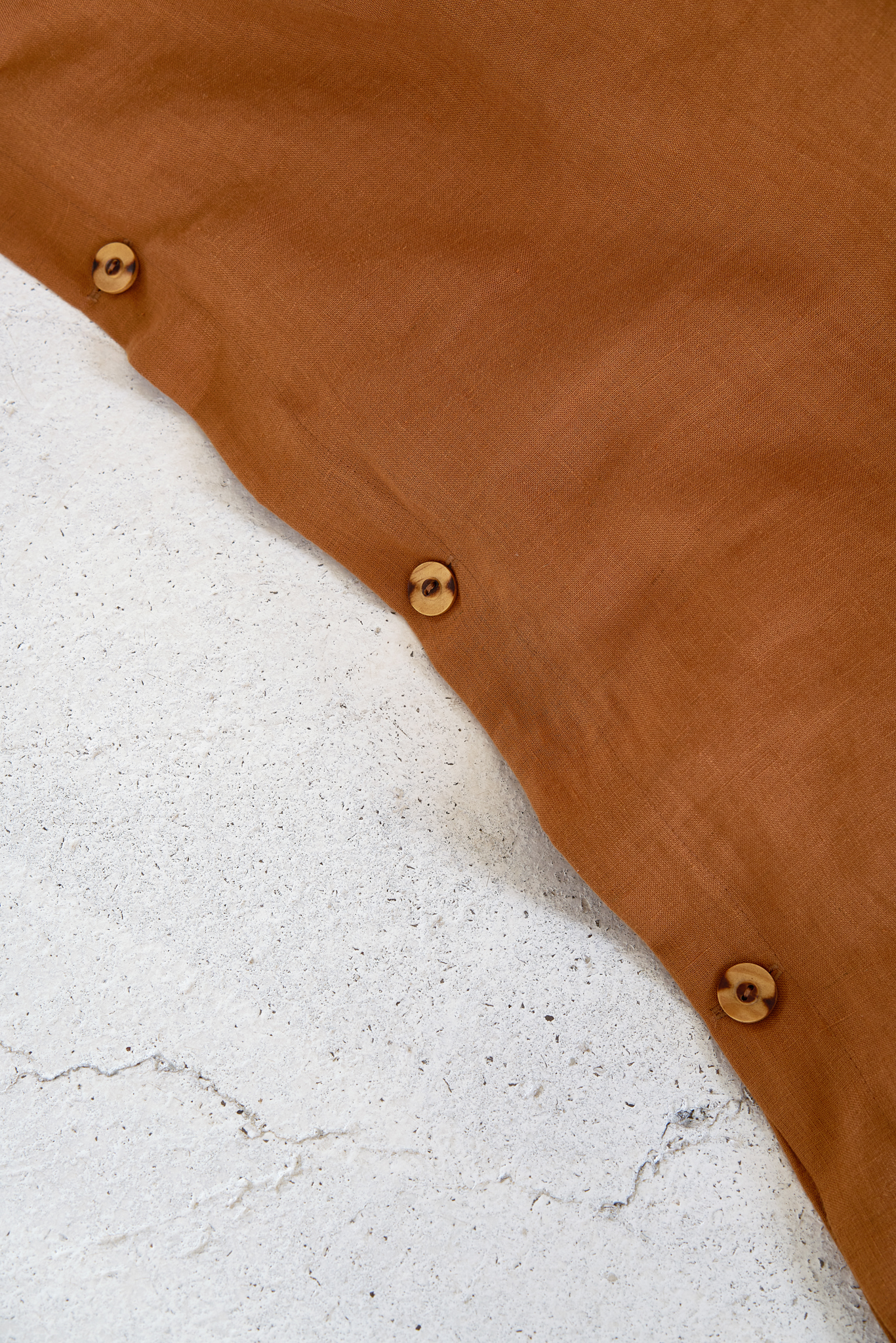 Terracotta linen apron detail showing wooden buttons and craftsmanship